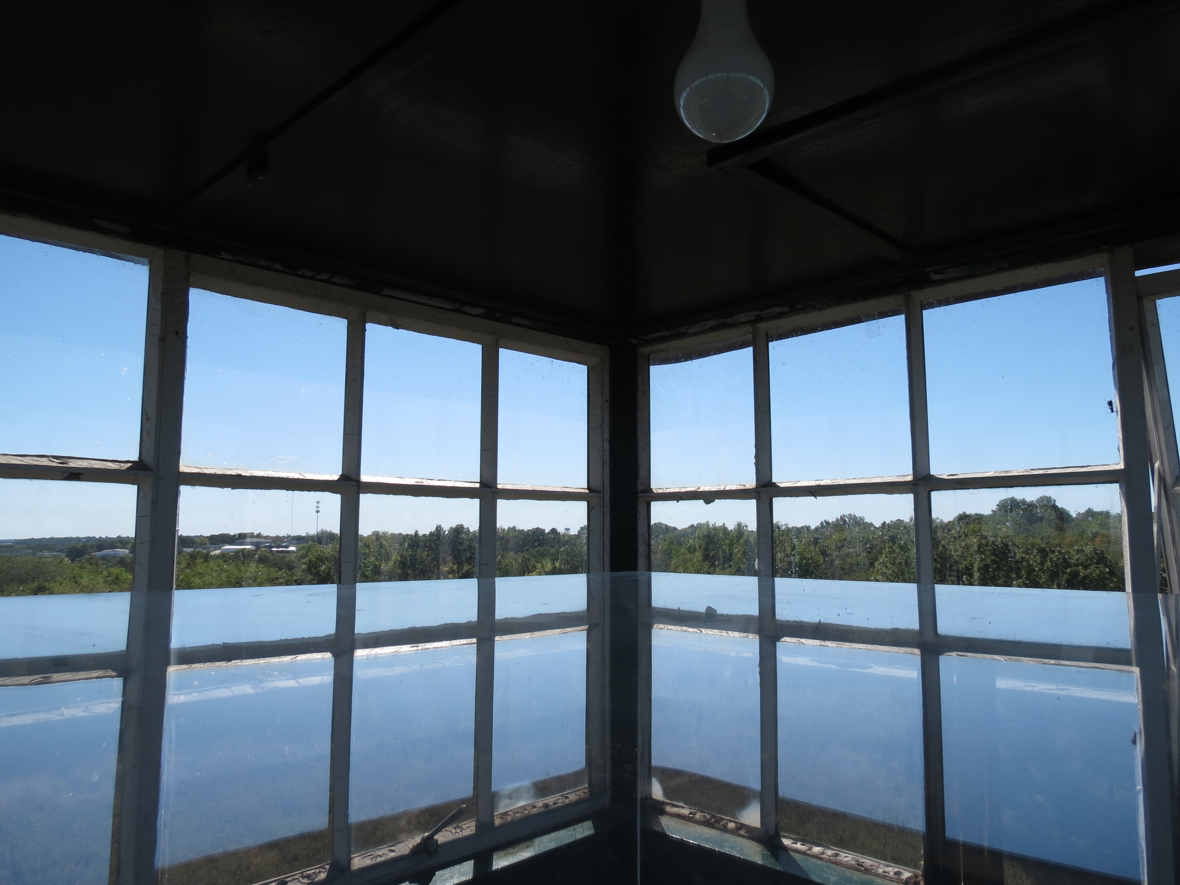 Inside of the fire tower sits an Osborne Fire Finder in a glass case. The sun coming in from the windows reflects the scenery, creating a mirror-effect. 