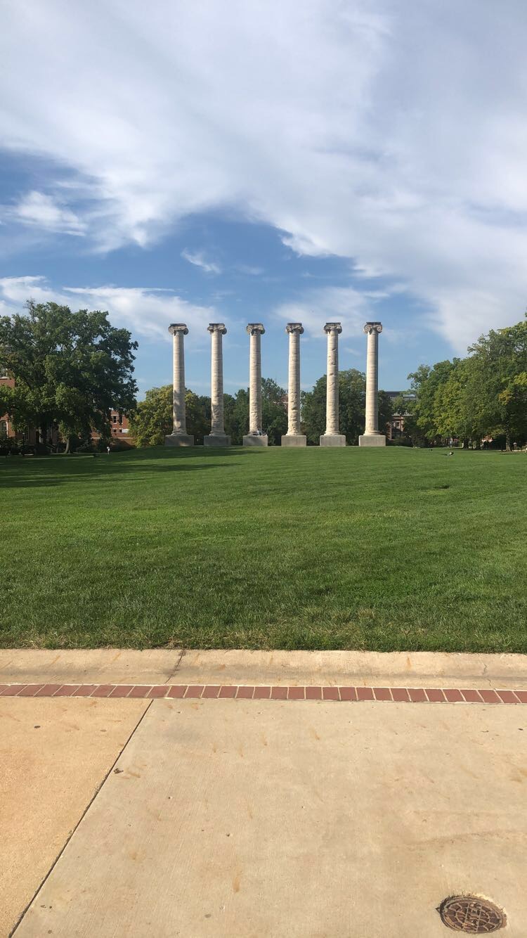 The six columns of the Francis Quad stand against Jesse Hall and a clear clue sky.